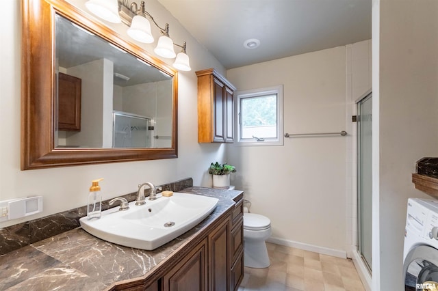 bathroom featuring vanity, washer / dryer, a shower with door, and toilet