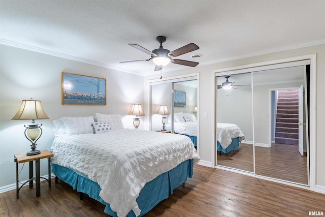 bedroom featuring multiple closets, ornamental molding, dark hardwood / wood-style floors, and ceiling fan