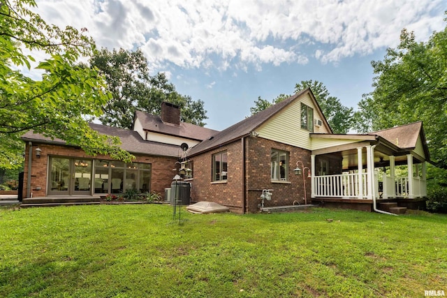 back of property with central AC unit, a yard, and a porch