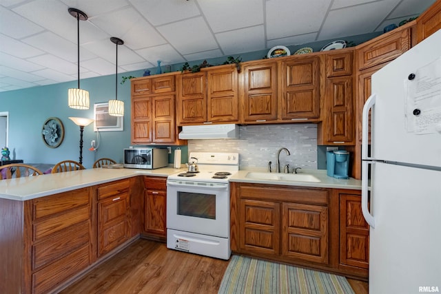 kitchen with tasteful backsplash, sink, hanging light fixtures, kitchen peninsula, and white appliances