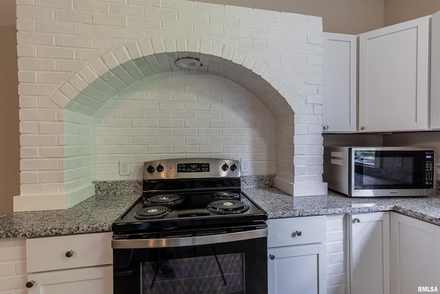 kitchen with stone countertops, white cabinetry, and appliances with stainless steel finishes