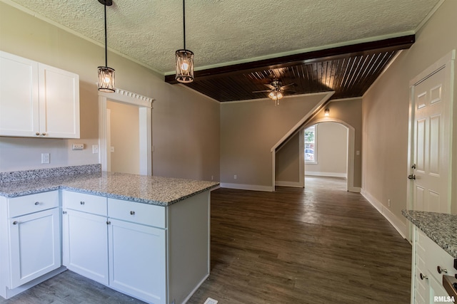 kitchen featuring kitchen peninsula, light stone counters, dark hardwood / wood-style flooring, and white cabinets