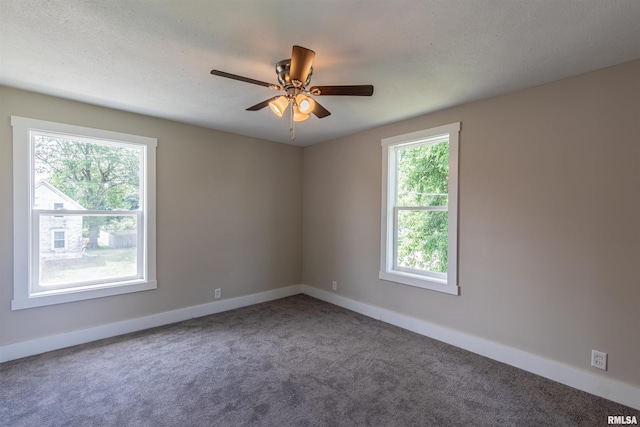 carpeted spare room featuring ceiling fan and plenty of natural light