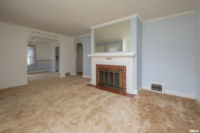 unfurnished living room featuring crown molding, carpet floors, a chandelier, and a brick fireplace