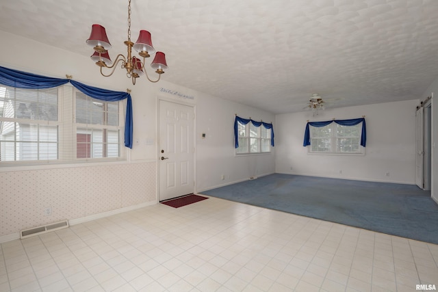 entrance foyer featuring ceiling fan with notable chandelier, a healthy amount of sunlight, and a textured ceiling