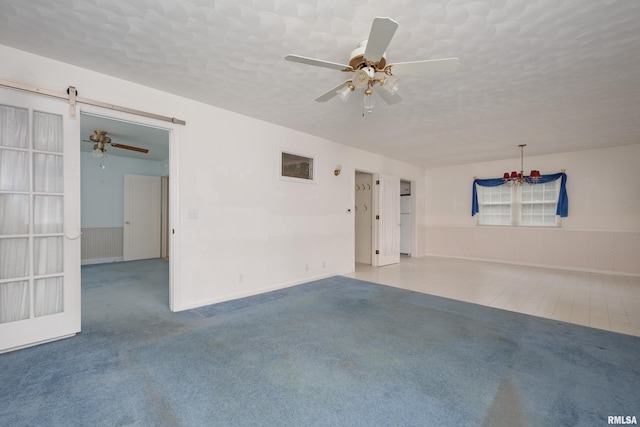 spare room featuring a textured ceiling, a barn door, and light carpet