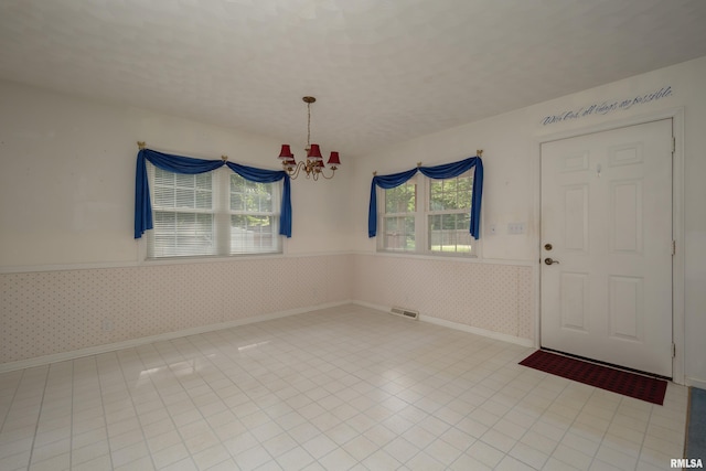 foyer with light tile patterned flooring and an inviting chandelier