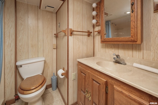 bathroom featuring wooden walls, vanity, and toilet