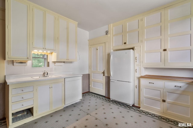 kitchen featuring sink, cream cabinetry, light tile patterned floors, and white appliances