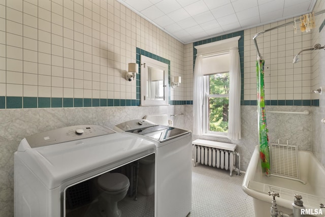 washroom featuring light tile patterned flooring, radiator, and tile walls