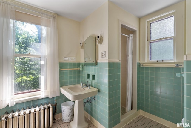 bathroom with radiator, a healthy amount of sunlight, and tile walls