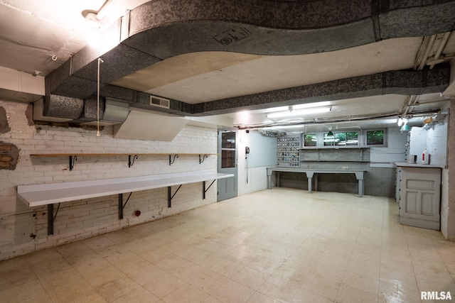 basement with brick wall and light tile patterned floors