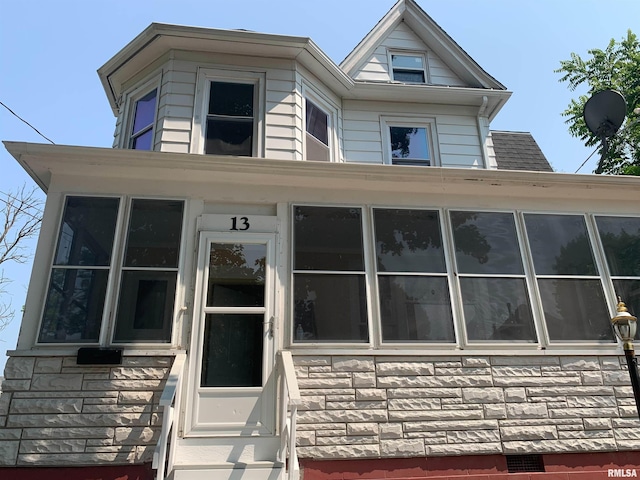 view of front of house with entry steps, stone siding, and roof with shingles