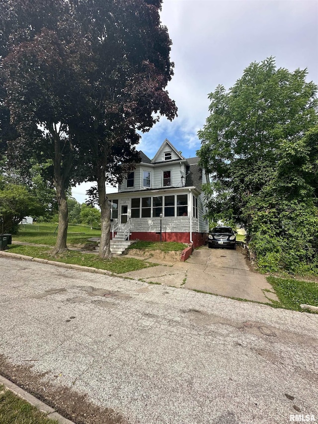 view of front of property featuring driveway, a sunroom, and entry steps