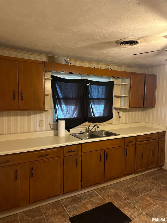 kitchen with dark tile patterned floors, sink, and a textured ceiling