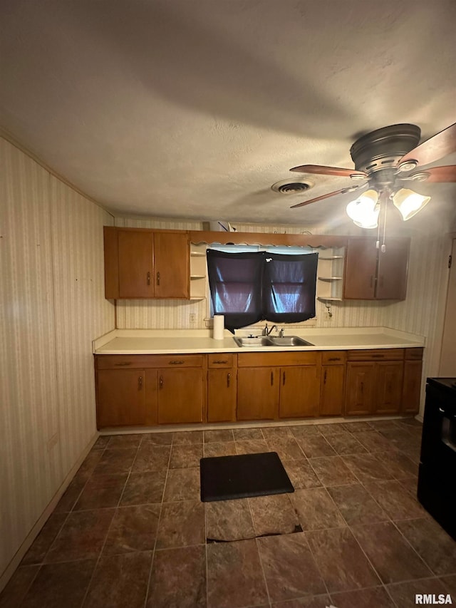 kitchen featuring range, sink, ceiling fan, and dark tile patterned floors