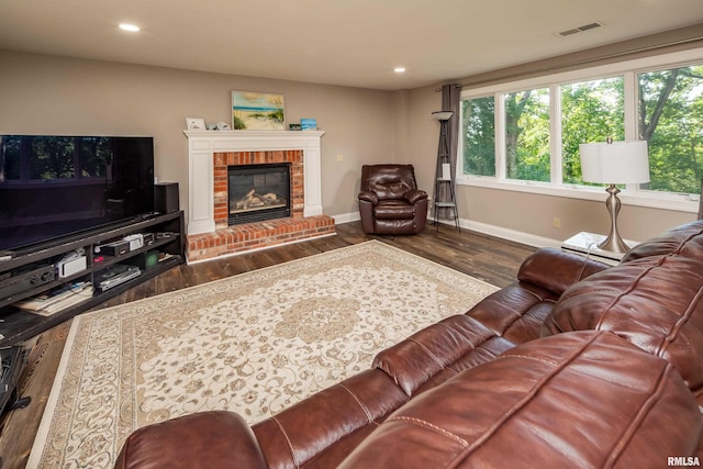 living room featuring dark hardwood / wood-style floors and a brick fireplace