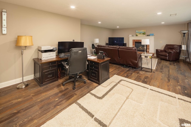 office with dark wood-type flooring and a fireplace