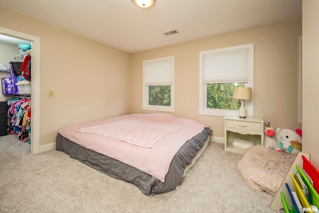 bedroom featuring a closet, light colored carpet, and a walk in closet