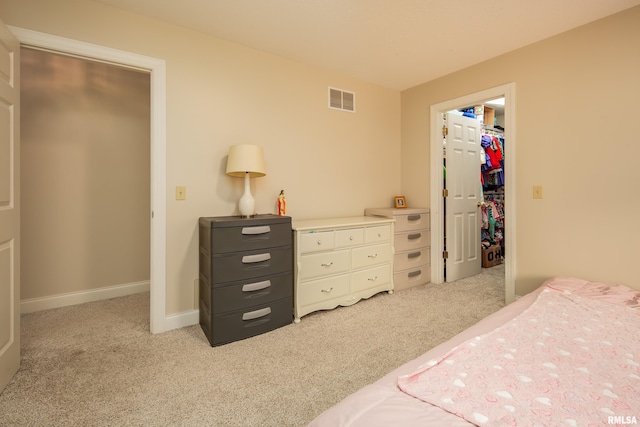 bedroom featuring a closet, light carpet, and a spacious closet