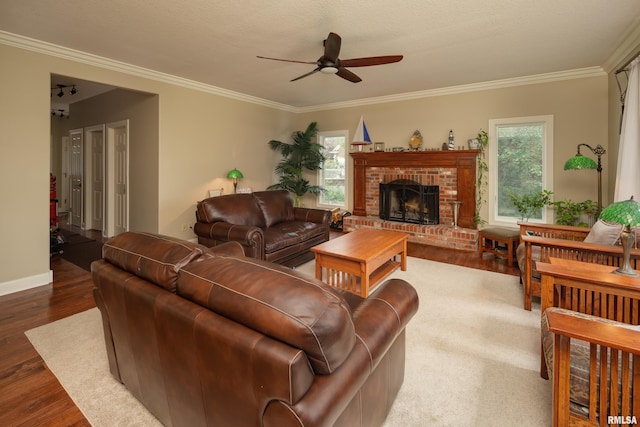 living room with dark wood-type flooring, ceiling fan, a fireplace, and ornamental molding