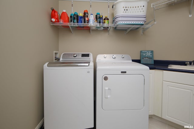 clothes washing area with cabinets, washing machine and dryer, and sink