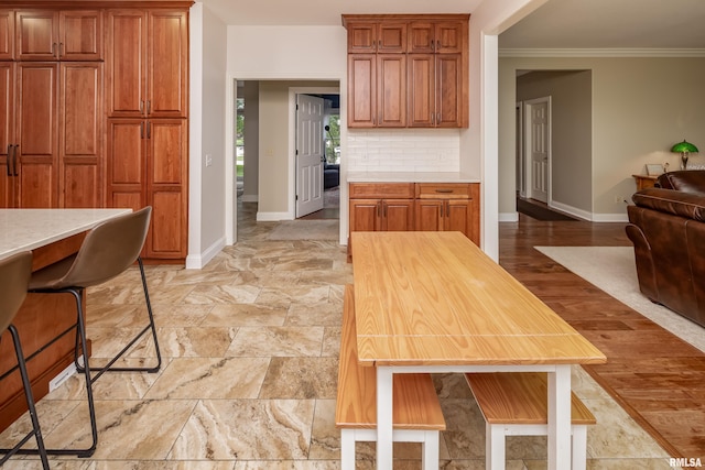 kitchen featuring crown molding, light hardwood / wood-style floors, and tasteful backsplash