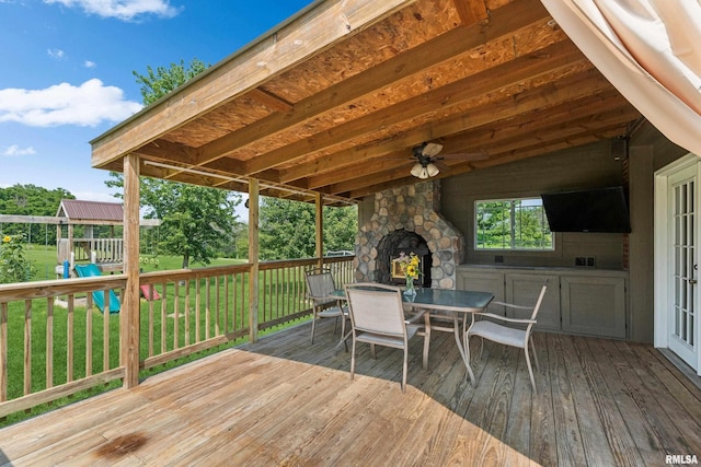 wooden deck with a lawn and an outdoor stone fireplace