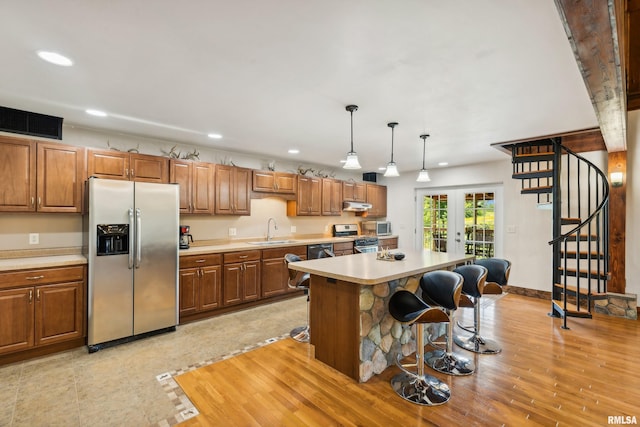 kitchen with sink, a breakfast bar area, a kitchen island, pendant lighting, and stainless steel appliances