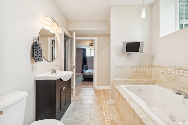 bathroom featuring tiled tub, ceiling fan, tile patterned flooring, vanity, and toilet