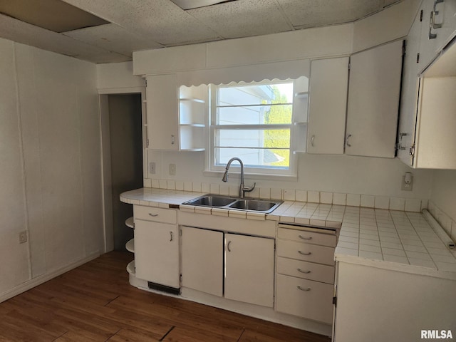 kitchen with white cabinetry, sink, tile counters, and a drop ceiling