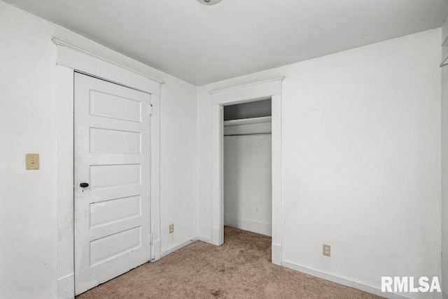 unfurnished bedroom with light colored carpet and a closet