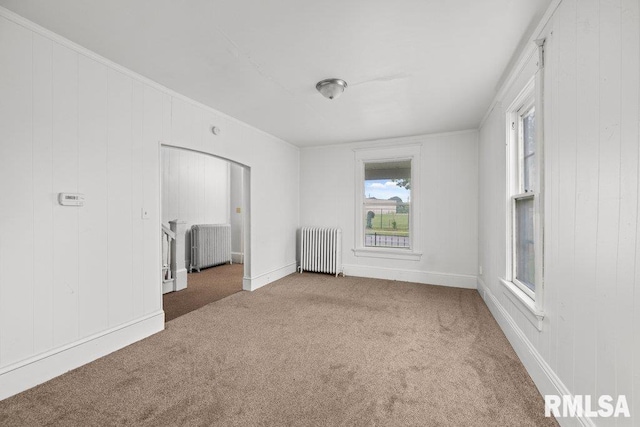 unfurnished living room featuring light carpet, crown molding, and radiator heating unit