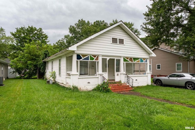 view of front facade with central AC unit, a sunroom, and a front lawn