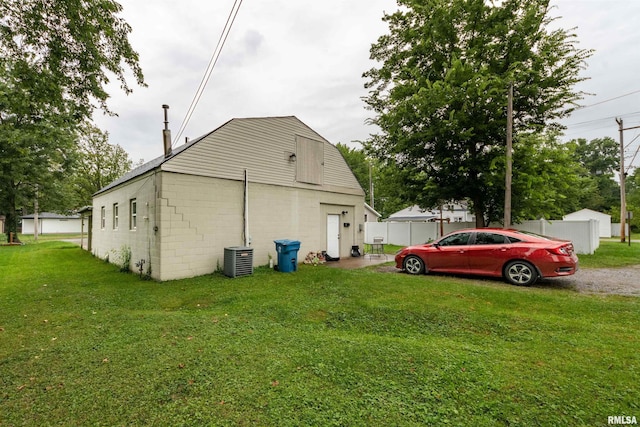 view of side of property featuring central AC unit and a lawn