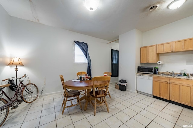 kitchen with white dishwasher, light tile patterned floors, and light brown cabinets