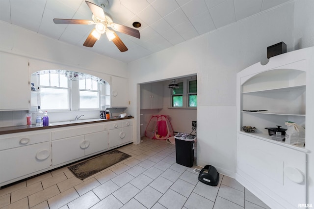 kitchen featuring white cabinetry, sink, light tile patterned floors, and ceiling fan