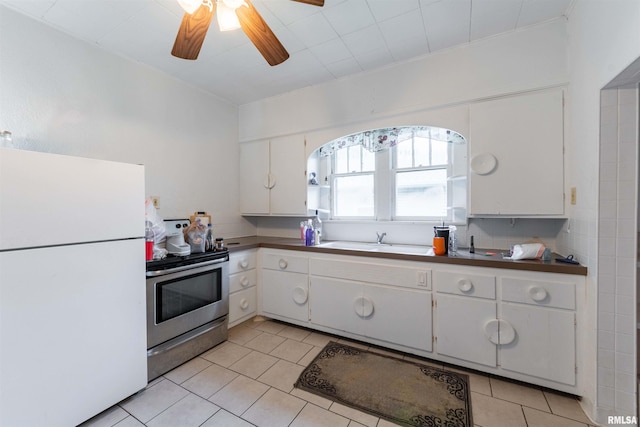 kitchen featuring sink, electric range, white refrigerator, white cabinets, and light tile patterned flooring