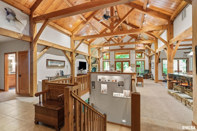 stairway featuring beam ceiling, wood ceiling, ceiling fan, light colored carpet, and high vaulted ceiling