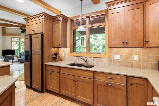 kitchen with beamed ceiling, light hardwood / wood-style flooring, sink, decorative light fixtures, and paneled refrigerator