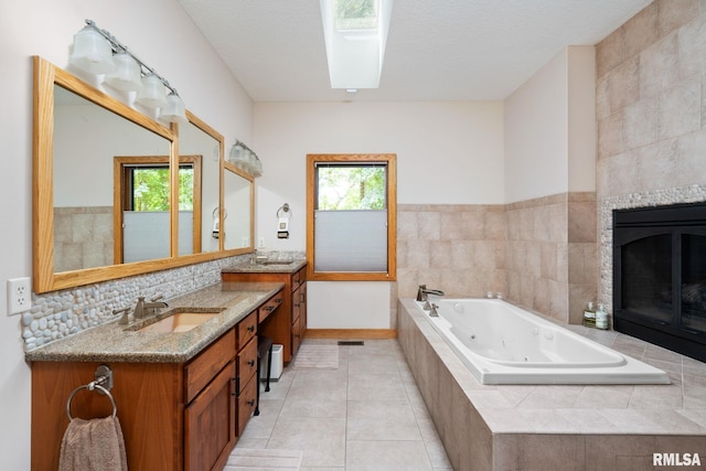 bathroom featuring tiled bath, a tiled fireplace, tile patterned flooring, and plenty of natural light