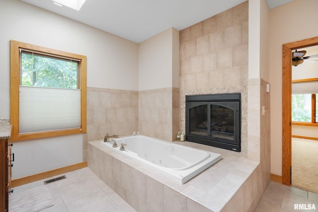 bathroom featuring tile patterned floors, ceiling fan, tile walls, a tile fireplace, and a relaxing tiled tub