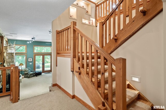 stairway featuring a notable chandelier, light colored carpet, and a textured ceiling