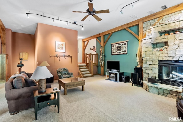 living room with a stone fireplace, light carpet, and rail lighting