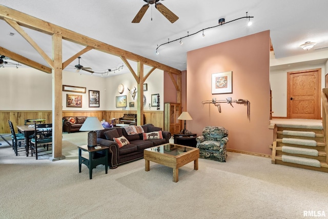 carpeted living room featuring beamed ceiling, track lighting, and ceiling fan