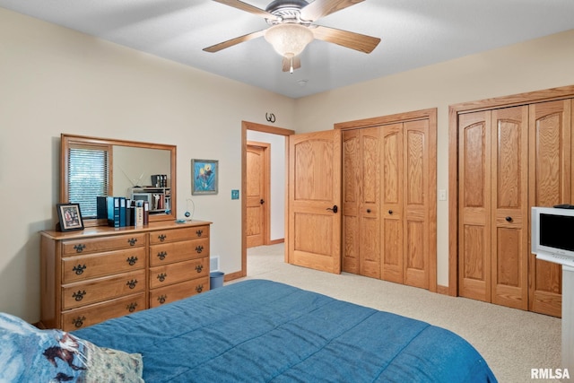 carpeted bedroom with ceiling fan and two closets