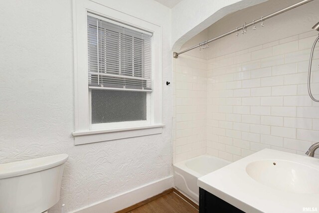 full bathroom featuring vanity, wood-type flooring, tiled shower / bath, and toilet