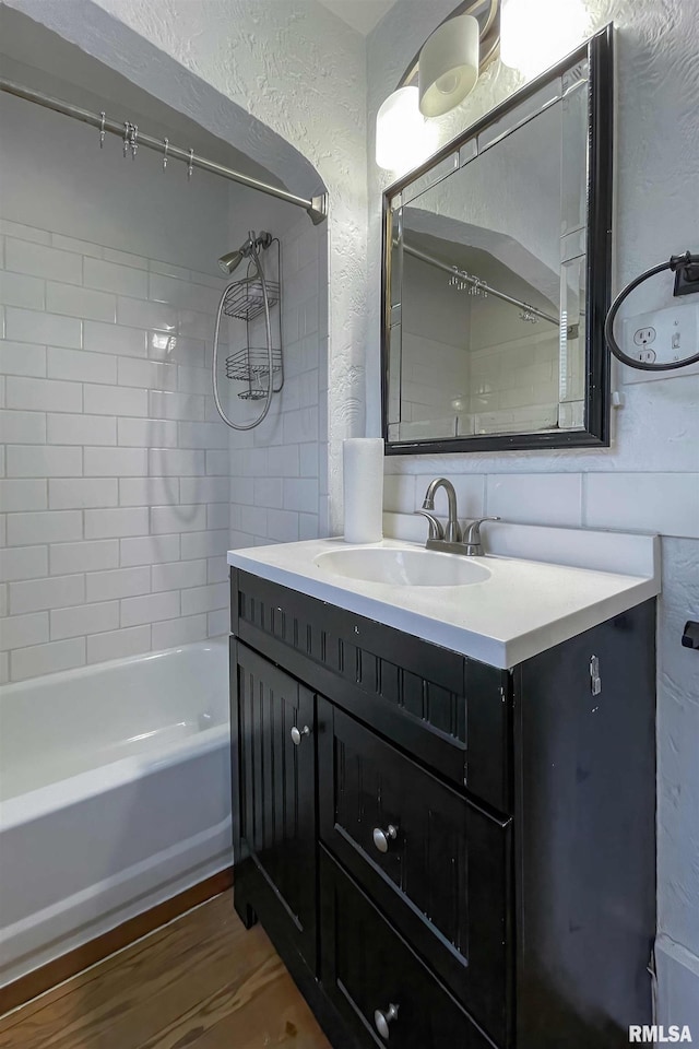 bathroom with hardwood / wood-style flooring, vanity, and tiled shower / bath