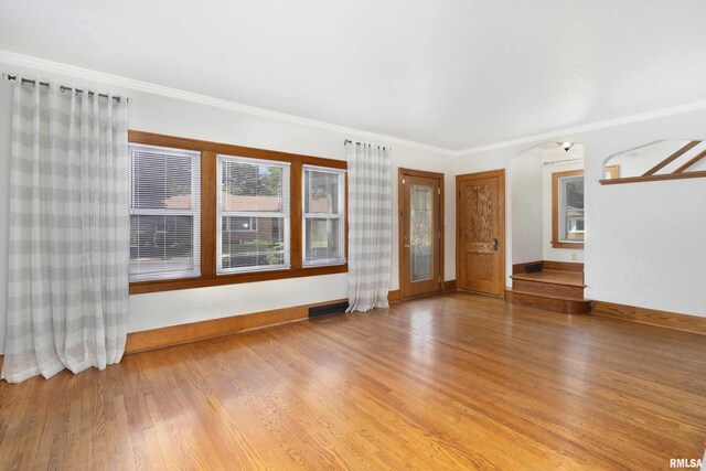 unfurnished living room with wood-type flooring and crown molding