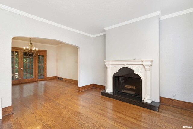 unfurnished living room with crown molding, wood-type flooring, and a notable chandelier